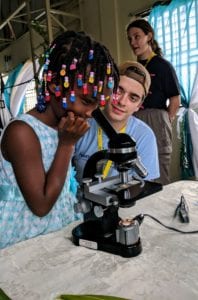 Kevin Carr teaches a Haitian student how to use a microscope. Photo by Professor Marcia Blackburn