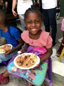 A child smiling after receiving food from the Health for Haiti class