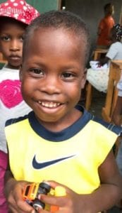 A smiling Haitian boy with a toy