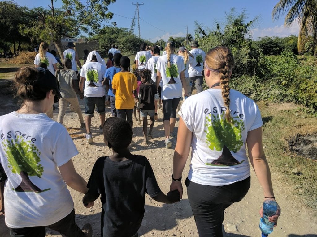 Health for Haiti students walk with a Haitian child