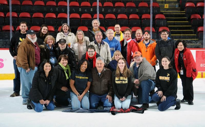 Alumni on the ice at the Floyd Maines Arena, posing for a photo