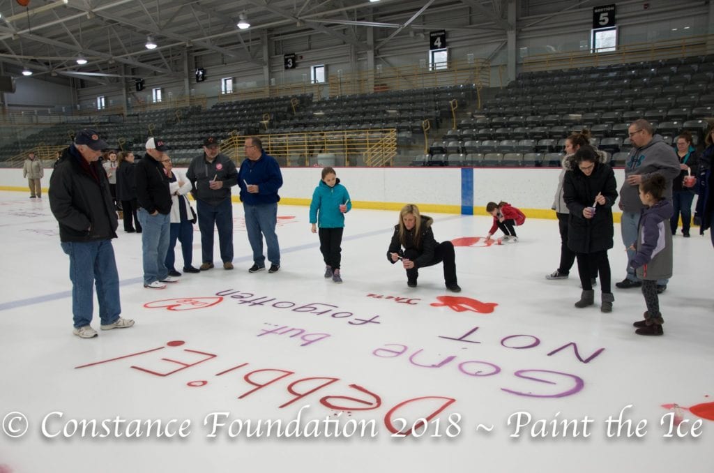 People painting messages on the Ice Center rink as part of Hockey 4 Hope