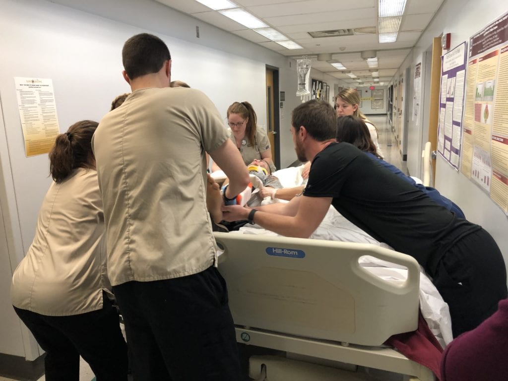 Nursing and Rad Tech students transfer a patient from a bed to a gurney at the Mock Disaster