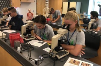 Students looking through microscopes at the Summer STEAM Academy