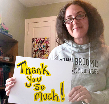 Jacqueline wears a SUNY Broome sweatshirt and holds a sign that says, " Thank you so much!" 