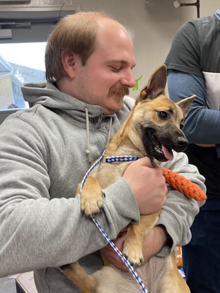 Man holding a shelter dog named "Carrot".