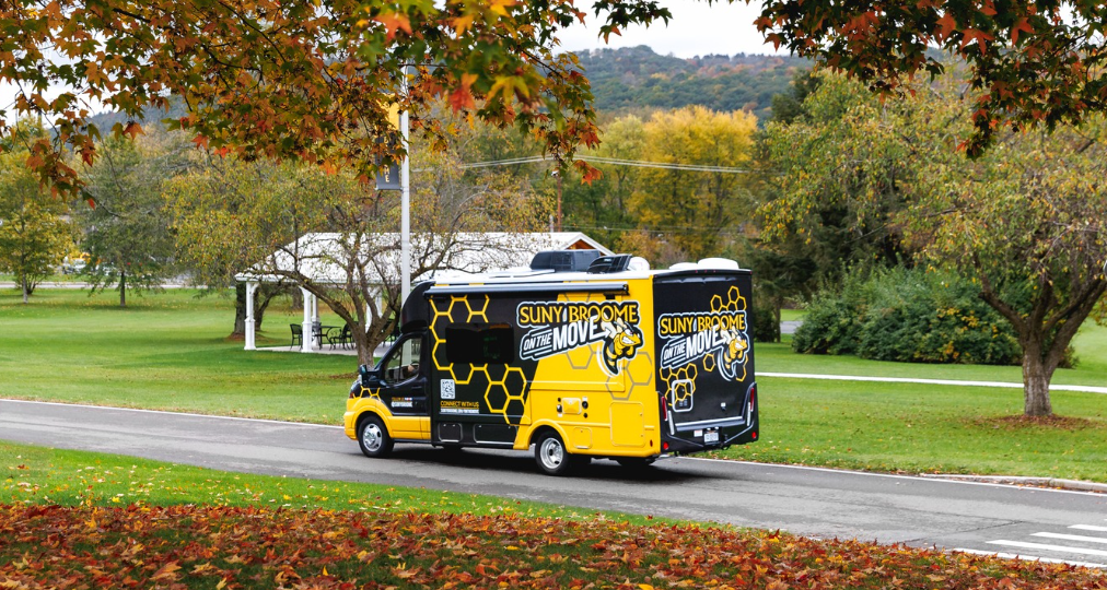 SUNY Broome On the Move: Mobile Enrollment Vehicle in a Broome County Autumn background.