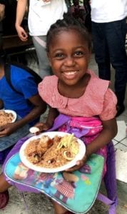 A smiling Haitian girl with food
