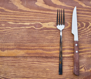 Knife and fork on empty table representing Food Insecurity