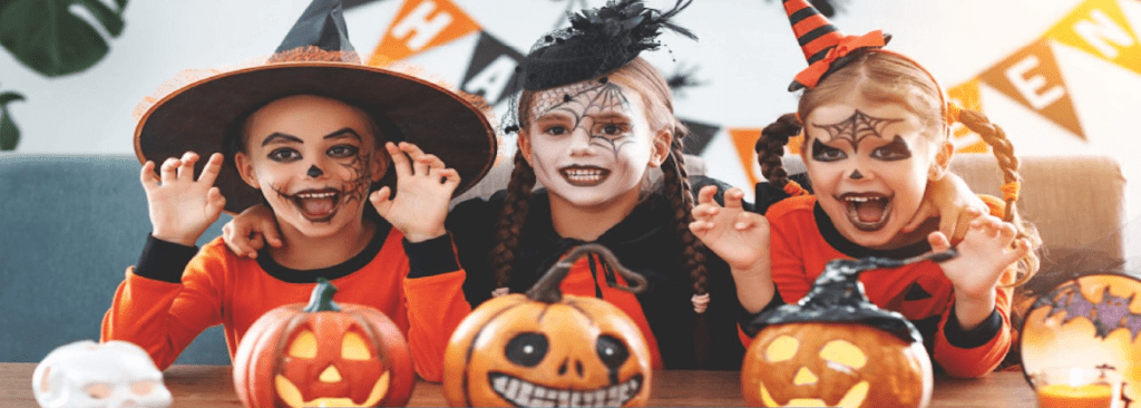 Halloween Kids in costumes at a table with painted pumpkins