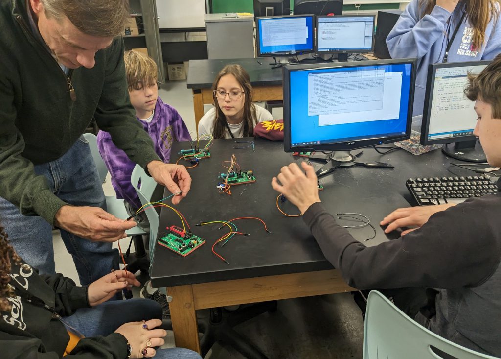 Professor Tom Grace, Engineering Science and Physics Department, works with students during a hands-on session.