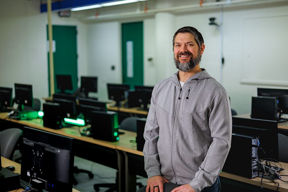 Professor Zwolinski stands in a computer science classroom. 