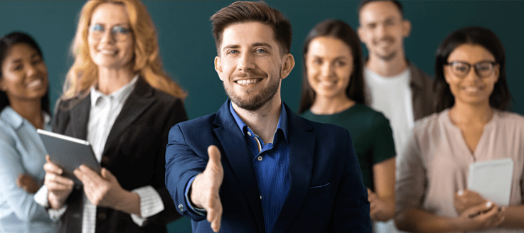 Toastmasters: group of smiling people. The center person has a hand out for a handshake.